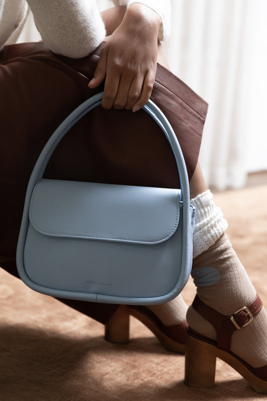 Model met Babyblauwe handtas met magnetische klepsluiting en twee rechtopstaande hengsels