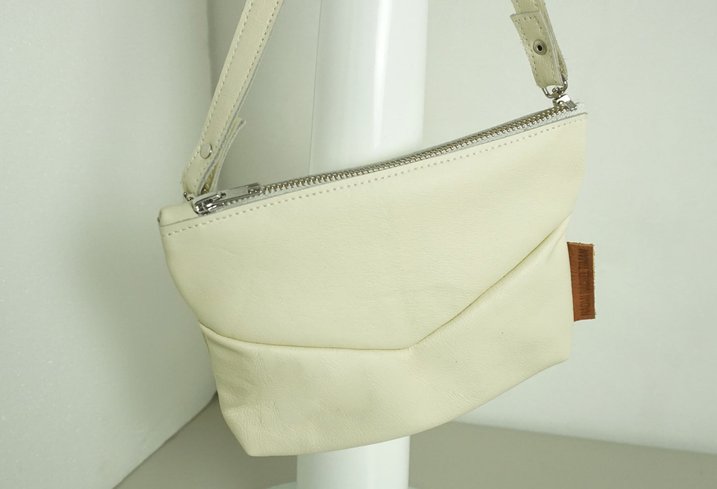 close up van Handtas van gerecycled creme leer met rits en v-stiksel