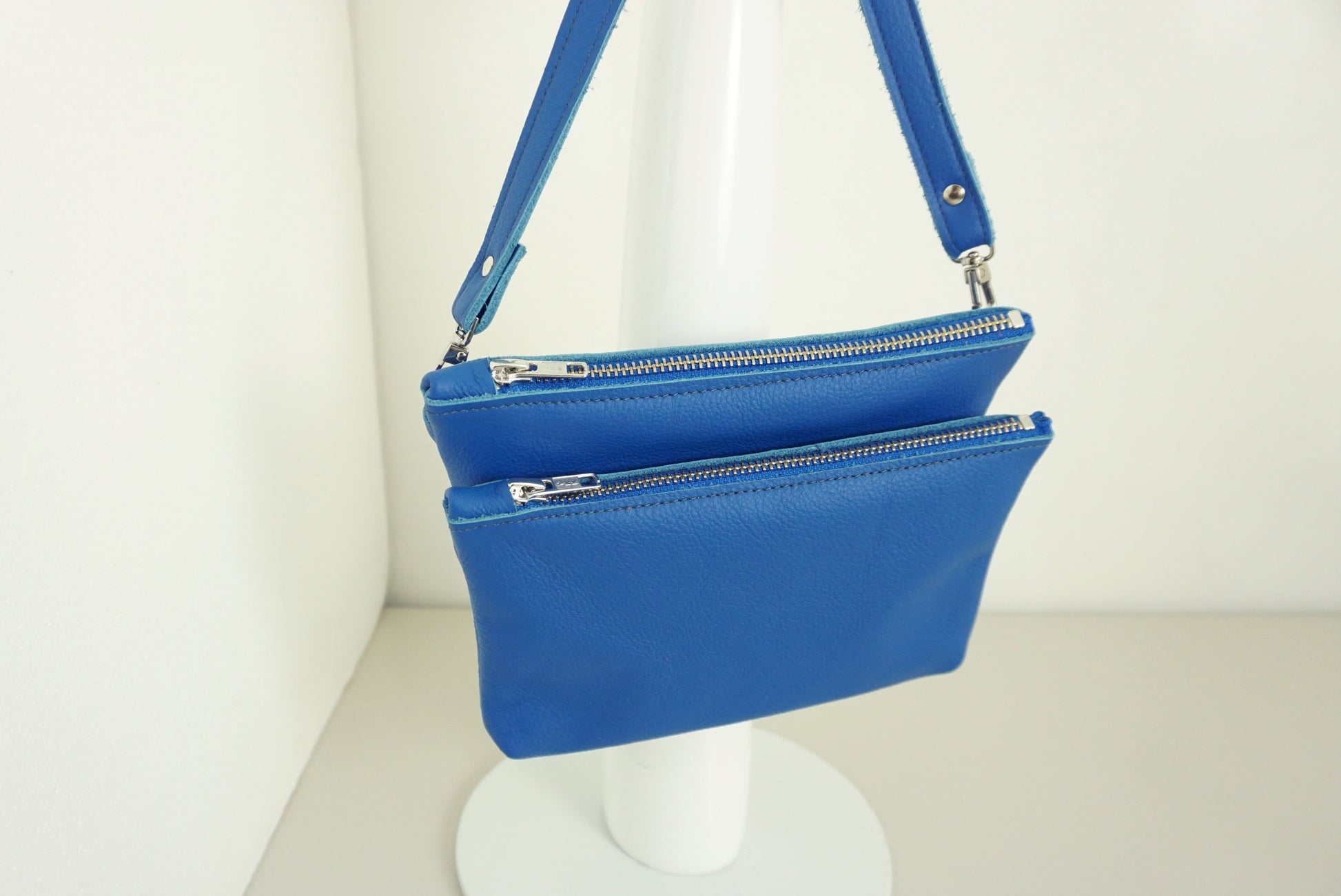 close up vabn Kobaltblauwe Schoudertas van twee vakken die met drukknopen vast zitten met rits van gerecycled leer