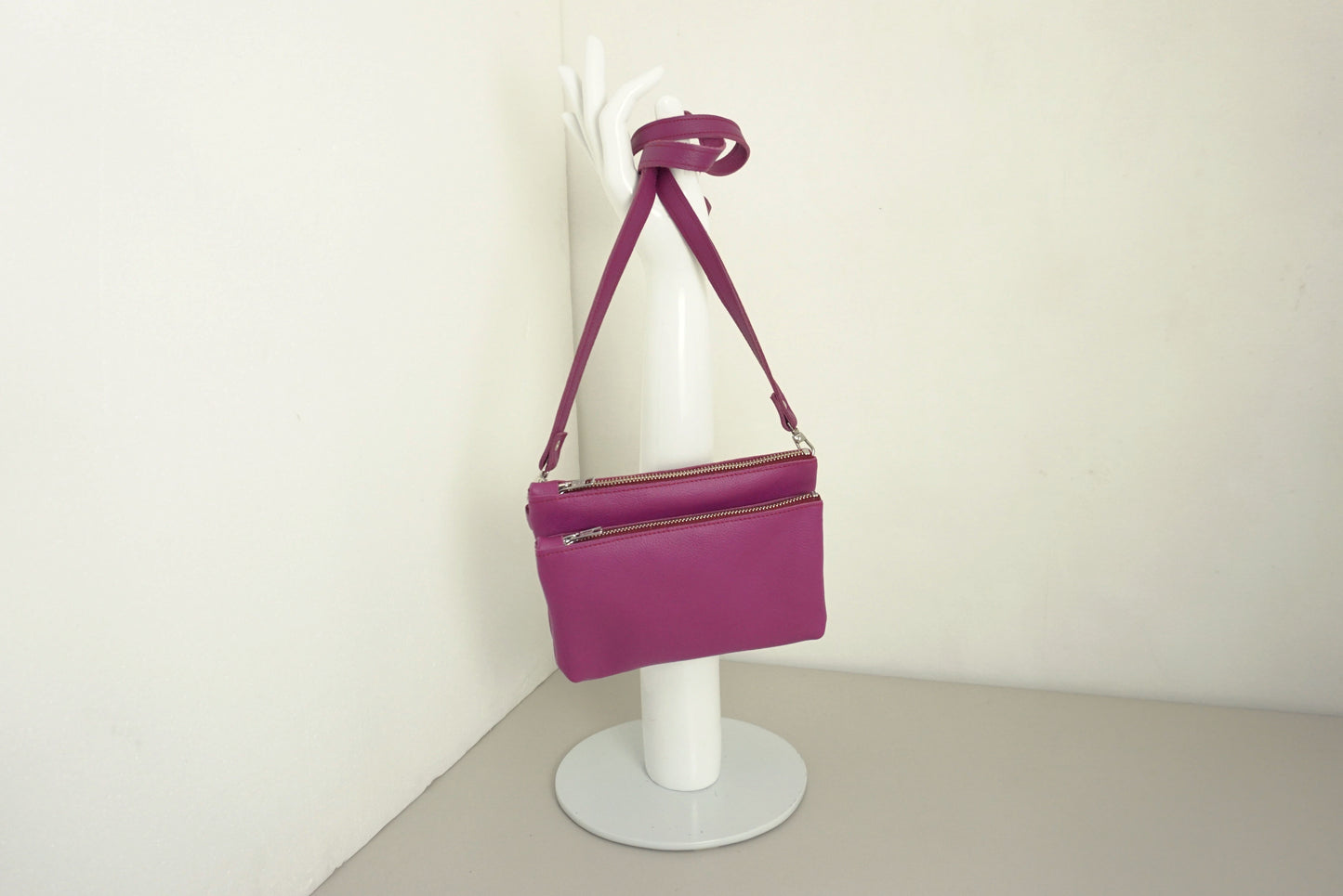 Magenta Schoudertas van twee vakken die met drukknopen vast zitten met rits van gerecycled leer met schouderband op standaard