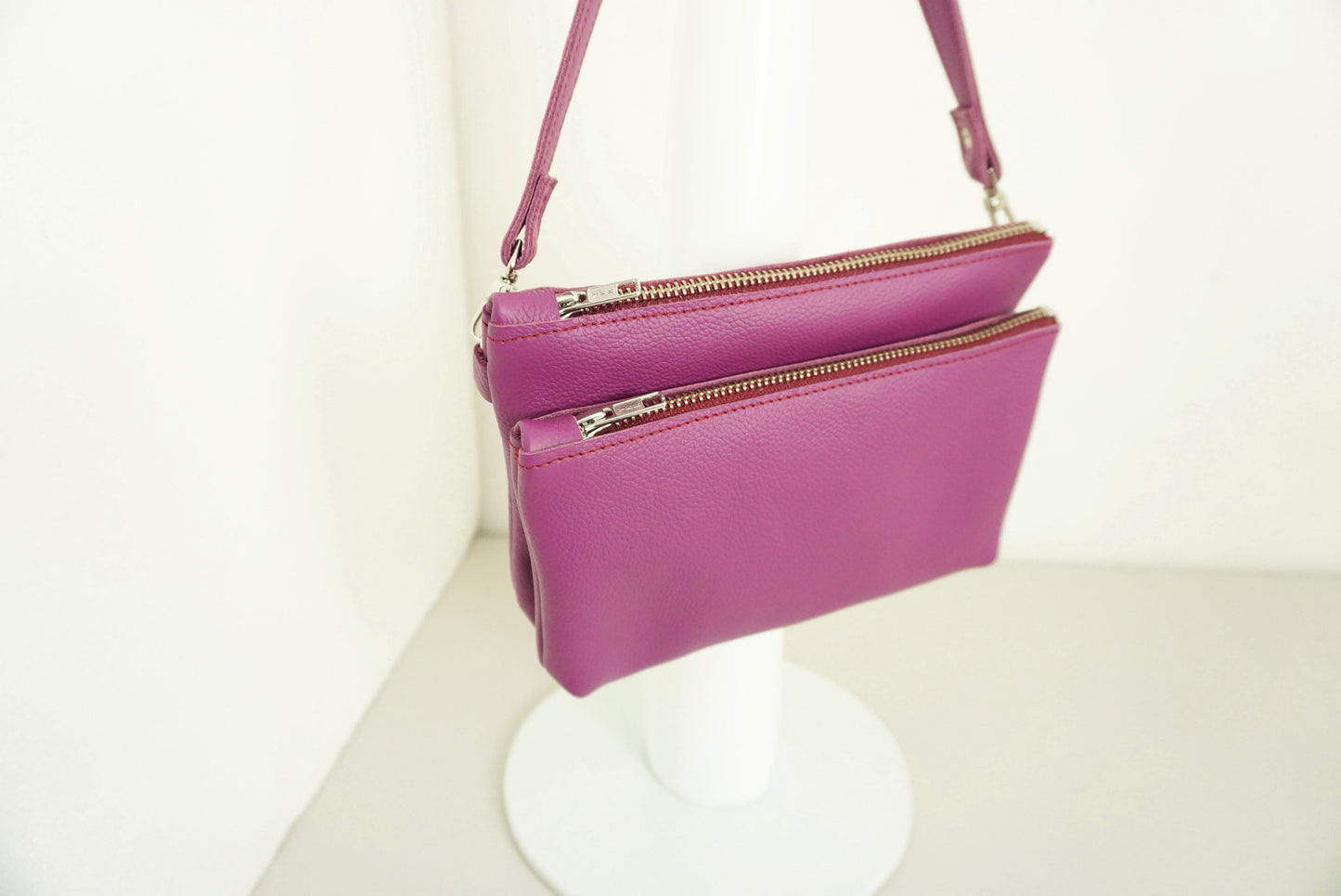 close up van Magenta Schoudertas van twee vakken die met drukknopen vast zitten met rits van gerecycled leer