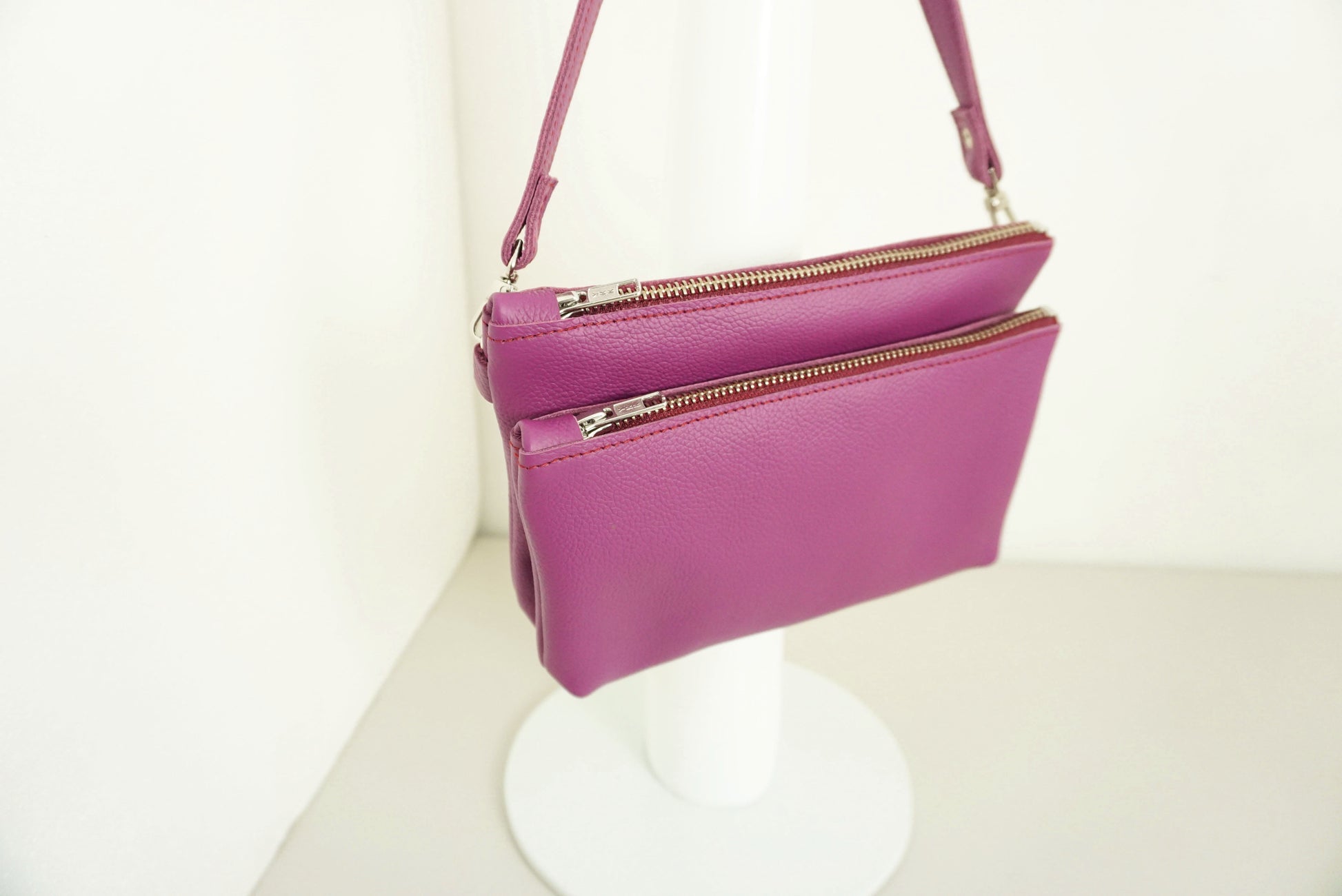 close up van Magenta Schoudertas van twee vakken die met drukknopen vast zitten met rits van gerecycled leer