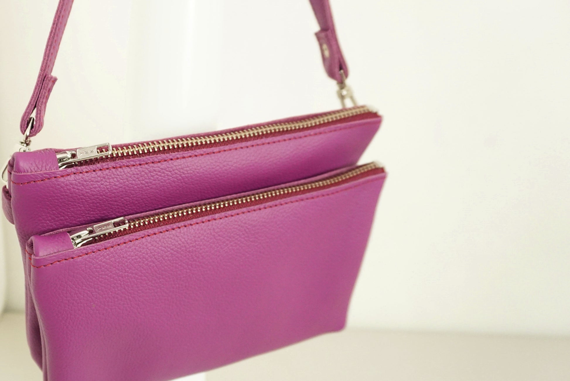 Magenta Schoudertas van twee vakken die met drukknopen vast zitten met rits van gerecycled leer