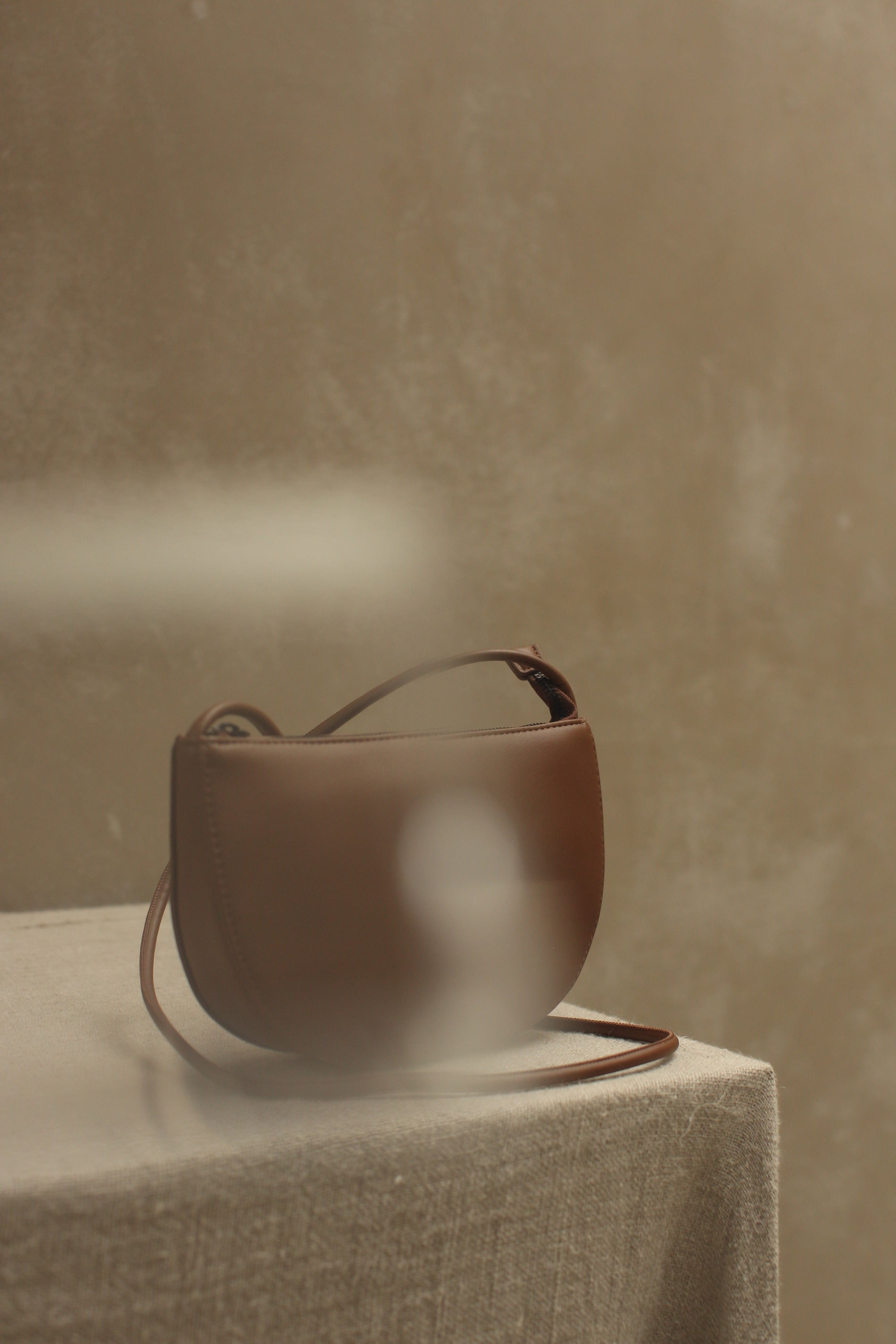 Donkerbruine schoudertas in halve maan vorm gemaakt van vega leer