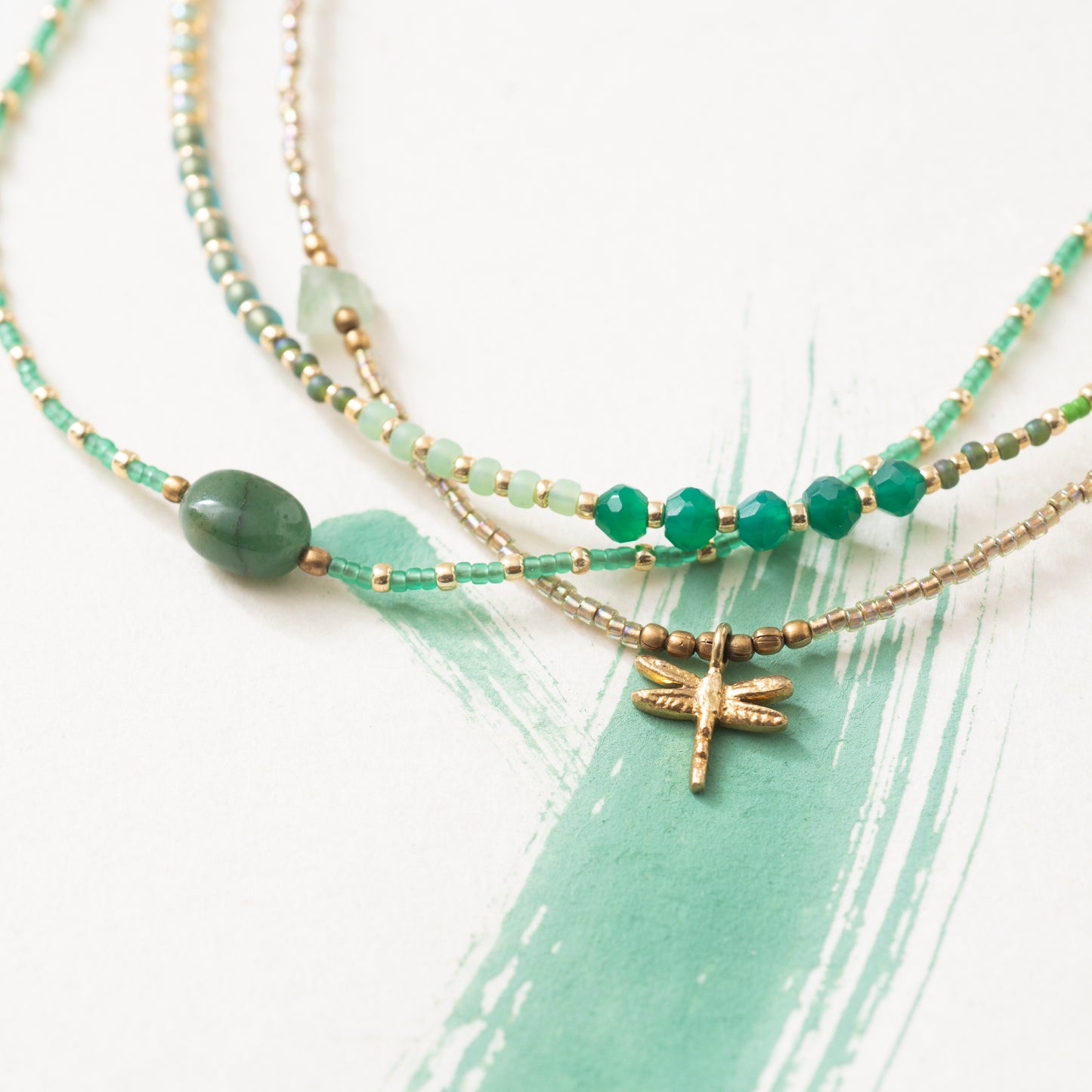 close-up foto Ketting confident van het merk A Beautiful Story met groene en gouden glaskralen en in het midden een aventurijn edelsteen. Samen met de Flowerfield en wildflower ketting.