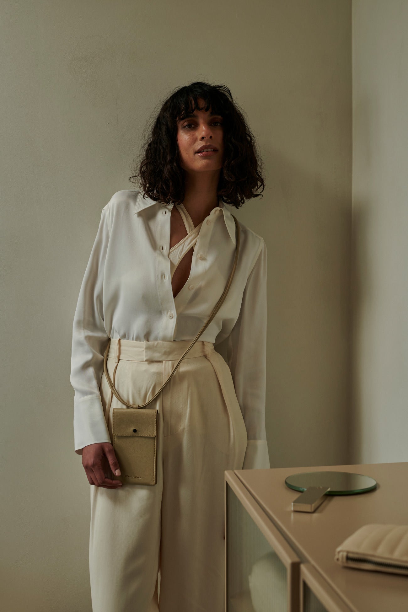 Model met telefoontas met schouderband en vak met drukknoop in de kleur pistach