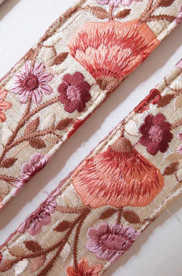 Close-up van Schouderband voor aan tas of telefoon met kleine roze geborduurde bloemen