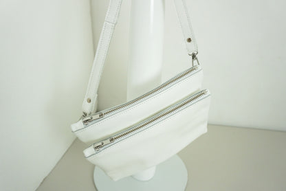 Schoudertas van twee vakken die met drukknopen vast zitten met rits van wit gerecycled leer