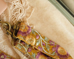 closeup van handgemaakte telefoon/tasriem met veelkleurige bloemen op okergele stof