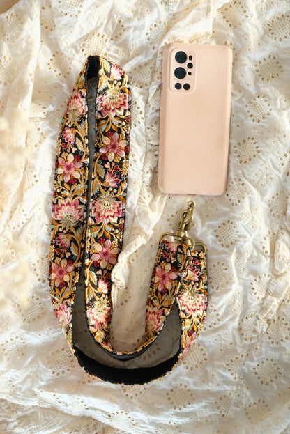 handgemaakte telefoon/tasriem van meerkleurige roze bloemen op zwarte stof vastgemaakt aan telefoonhoesje