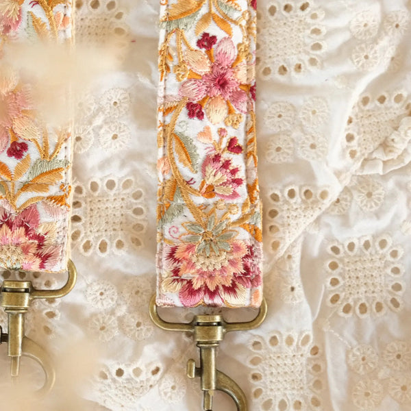closeup van handgemaakte telefoon/tasriem van meerkleurige roze bloemen op witte stof