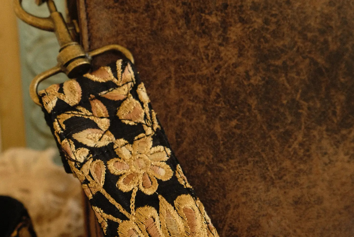 closeup handgemaakte telefoon/tasriem van geborduurde gouden bloemen op zwarte stof  