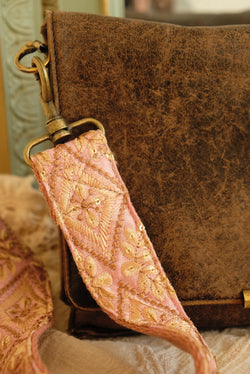 telefoon/tasriem van cremekleurige handgeborduurde ruiten met bloemen op roze stof vastgemaakt aan een tas